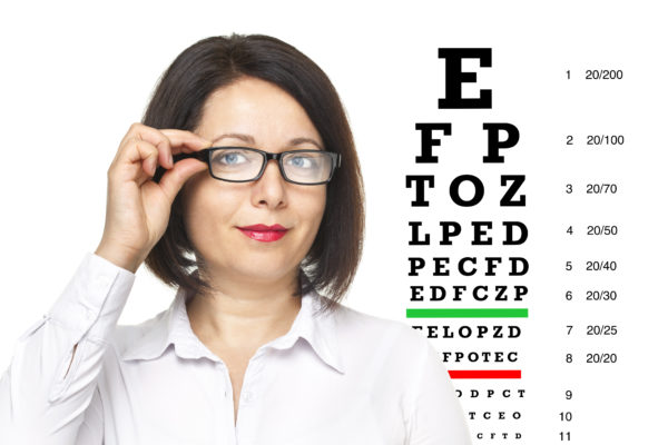 Woman with glasses standing next to an eye chart