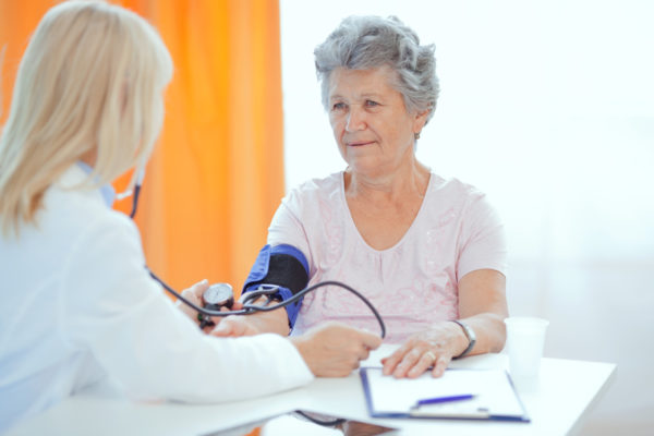 Mature female doctor measuring senior woman's blood