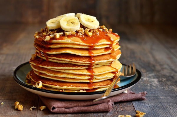 a stack of pancakes with bananas on top and syrup dripping down sides