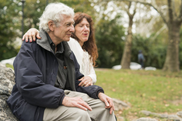 caregiver sitting with elderly man in a park