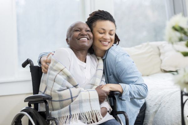 Young woman embraces her beautiful senior mother who is in a wheelchair.