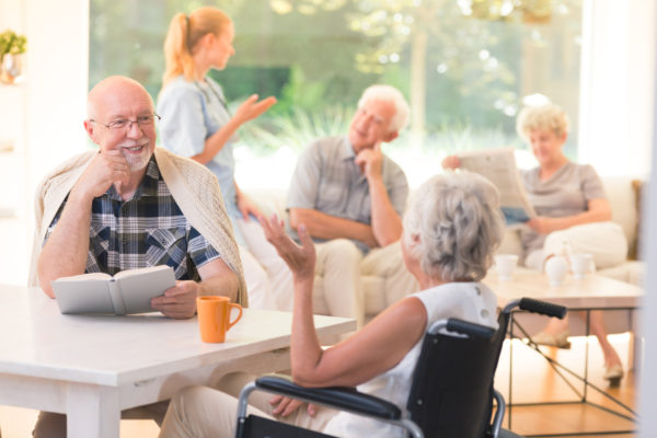 a group of seniors gathered a common area of an assisted living community