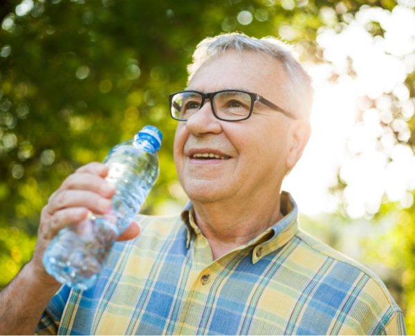 older man drinking from a water bottle outdoors
