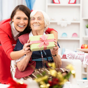 senior woman receiving gift from caregiver