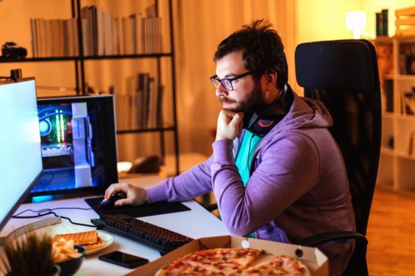 Man using computer with a pizza at his side
