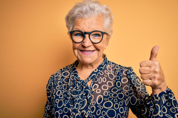 Elderly woman giving a thumbs up sign.