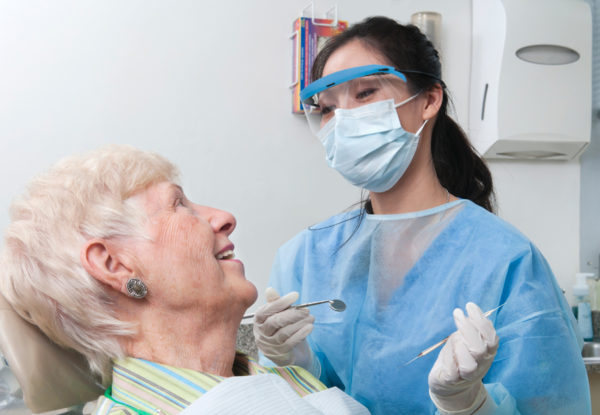 Masked dentist with older woman