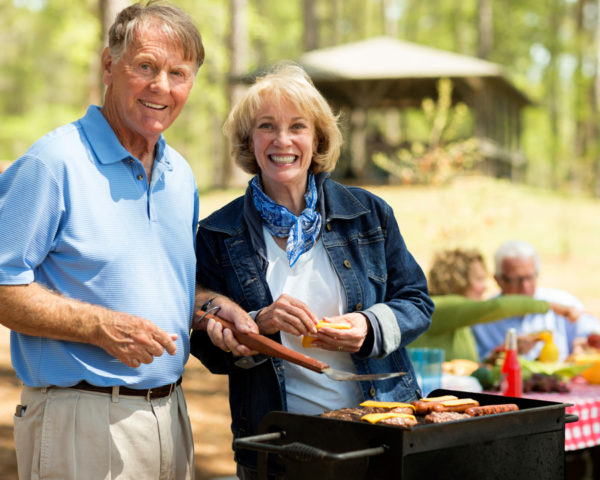 Sminling couple with barbeque grill
