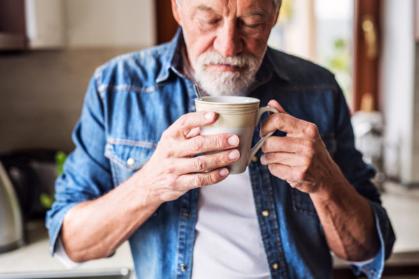 Senior man smelling cup of coffee