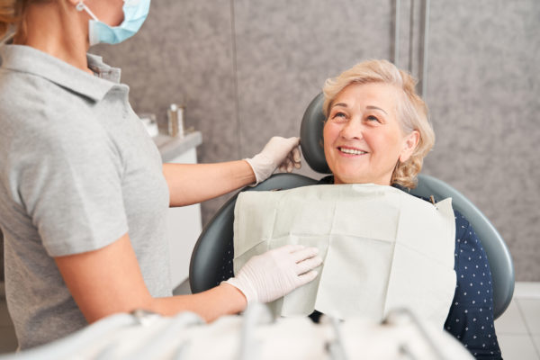 Woman sitting in dental chair and listening to dentist