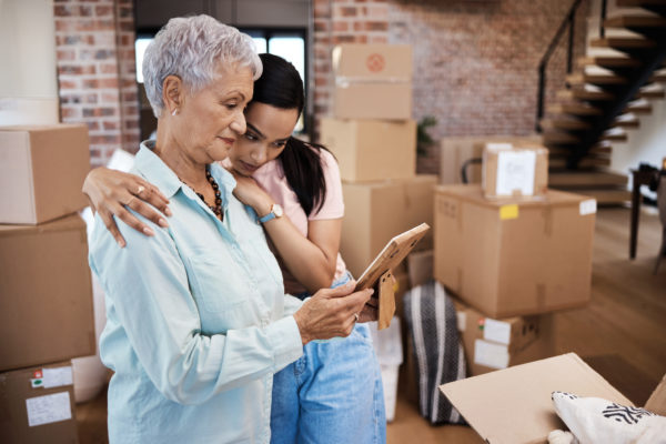 Shot of a senior woman looking at a photograph with her daughter while packing boxes on moving day